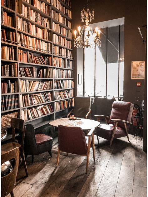 a room filled with lots of books and chairs next to a table in front of a book shelf