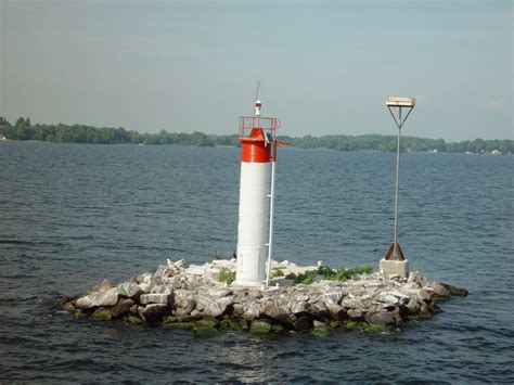 a red and white light tower sitting on top of a small island in the ...