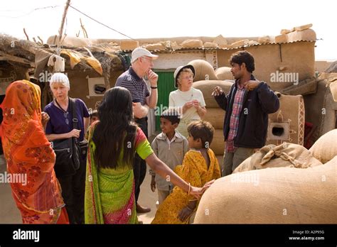 India Rajasthan Thar Desert remote village older western tourists talking to local people Stock ...