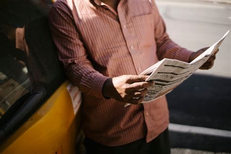 Crop ethnic male taxi driver reading newspaper in town · Free Stock Photo