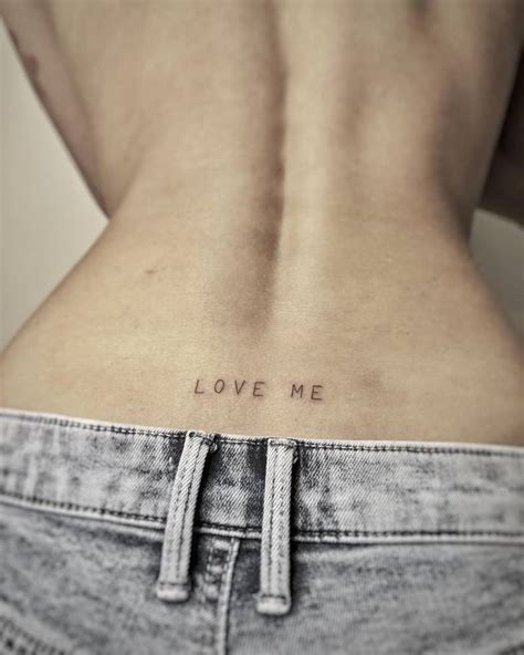 Tattoo that says "love me" located on the lower back.