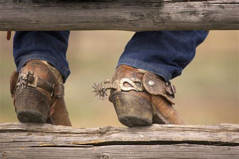 Boots and Spurs. Cowboy boots and spurs resting on a split rail fence ...