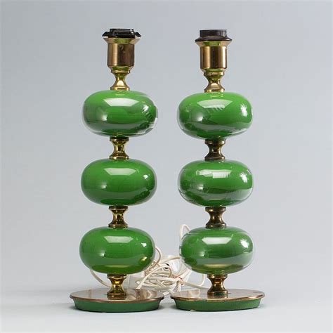 a pair of green glass lamps sitting on top of a white table next to each other