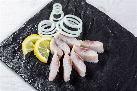 Fillet of lightly salted herring with spices, onion, garlic and lemon, top view - Creative ...