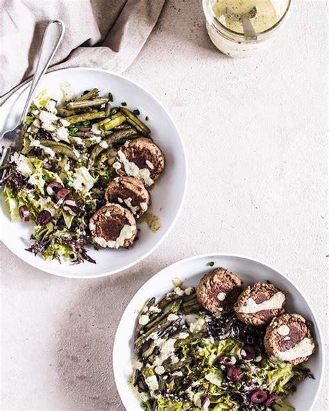 two white bowls filled with food next to a glass of wine on top of a table