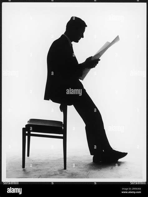 A silhouette of a businessman leaning against a chair reading a newspaper Stock Photo - Alamy