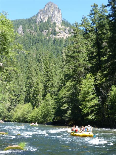 people are rafting down the river with mountains in the background