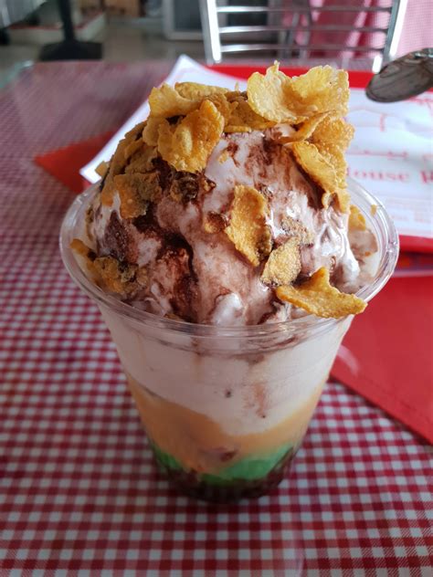 an ice cream sundae with chocolate chips and whipped cream in a glass on a checkered tablecloth