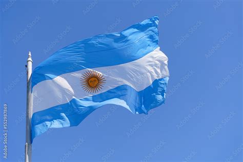 Argentinean flag on a clear blue sky background. Blue and white National symbol of Argentinean ...