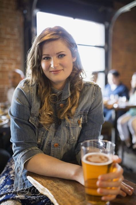 Portrait of smiling woman drinking beer in pub by Hero Images | Women drinking beer, Drinking ...