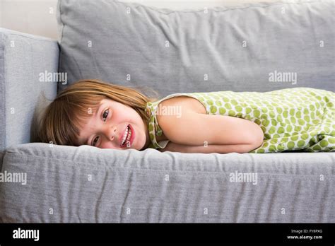 Portrait of smiling little girl lying on the couch Stock Photo - Alamy