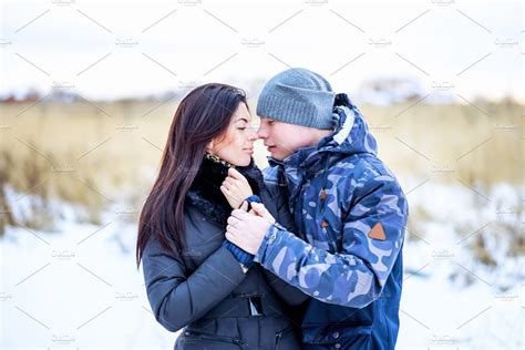 Beautiful young couple hugging in a park in winter snow-covered field, a gentle hug, fashion ...