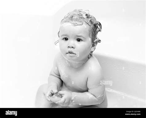 Funny baby bathes in bathtub with water and foam. Kids hygiene. Little child in a bathtub ...