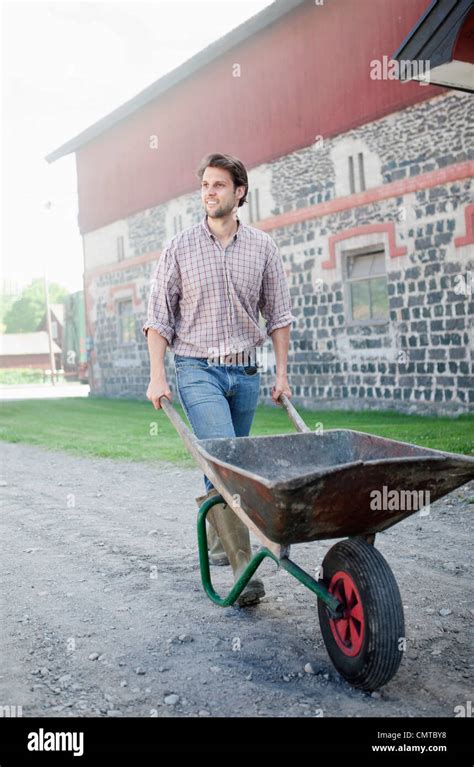 Man pushing wheelbarrow Stock Photo - Alamy