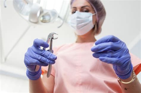 Premium Photo | Woman professional dentist holds forceps in the dental office pull out a tooth ...