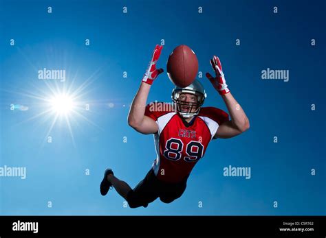 American Football player flying through the air to make the catch Stock Photo - Alamy