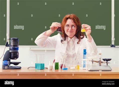 Chemistry teacher looks at reagent bubbles while sitting at a desk at ...