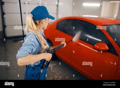 Female washer in uniform cleans the auto with high pressure gun in ...