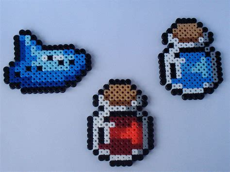 three pixel art magnets are displayed on a white surface with blue and red colors