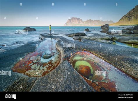 Woman standing on rocks on the beach, in front tide pool with formation Eye of Utakleiv ...