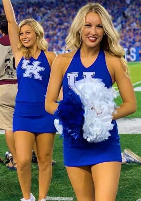 two cheerleaders walking on the field at a football game with their ...