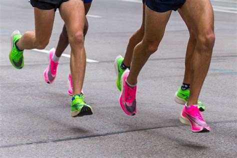 Legs of marathon runners wearing Nike ZoomX Vaporfly Next% running shoes in the pink and green ...
