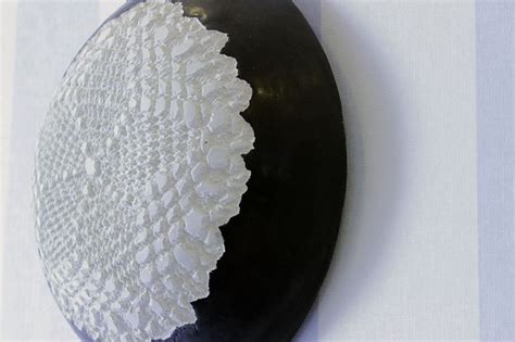 a black and white plate with lace on it sitting on a striped wallpapered surface