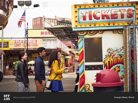 Friends waiting in line at amusement park ticket booth stock photo - OFFSET