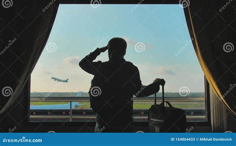 A Young Guy Looks at the Plane Taking Off from the Window of His Hotel ...