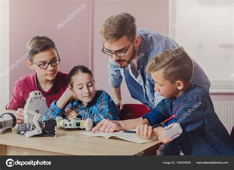 Stem education. Kids creating robots with teacher Stock Photo by ©Milkos 169250658