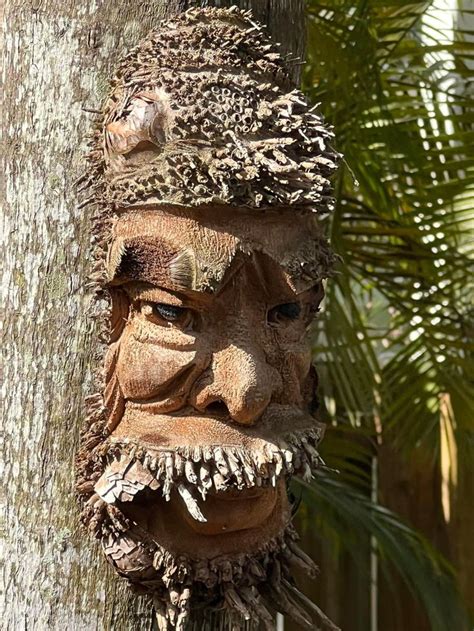 a tree with a face carved into it's trunk next to a palm tree