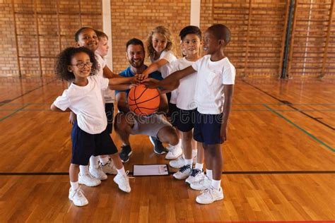 Schoolkids and Basketball Coach Forming Hand Stack and Looking at Camera in Basketball Court ...