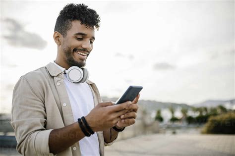 Happy man with wireless headphones using smart phone stock photo