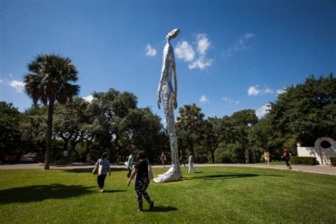 two people walking in the grass near a sculpture