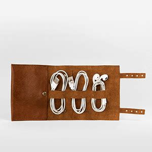 a brown leather case with four white cords in the middle and two plugs on each side