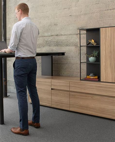 a man standing at a desk using a laptop computer