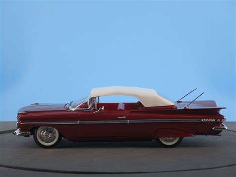 a red and white model car on a gray surface with a blue sky in the background