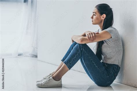 side view of beautiful upset brunette girl sitting and looking away ...