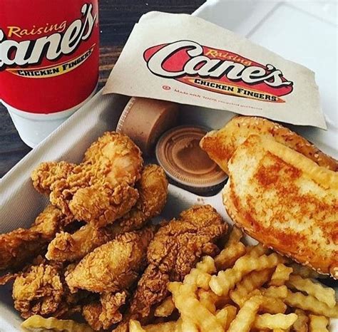 fried chicken, french fries and a drink on a tray next to a bag of cane's