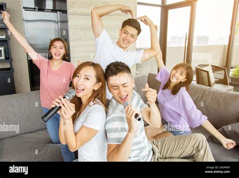 Group of friends playing karaoke at home Stock Photo - Alamy