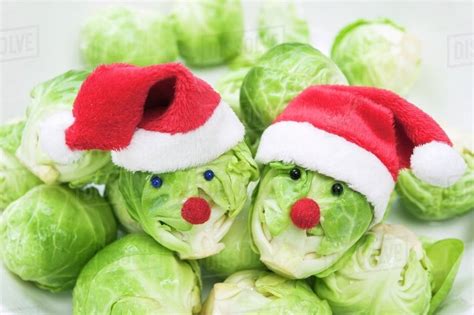 Two Brussels sprouts with faces wearing Christmas hats - Stock Photo - Dissolve