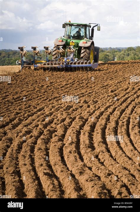 A farmer using his tractor to plough a field with a furrow press attached UK Stock Photo - Alamy