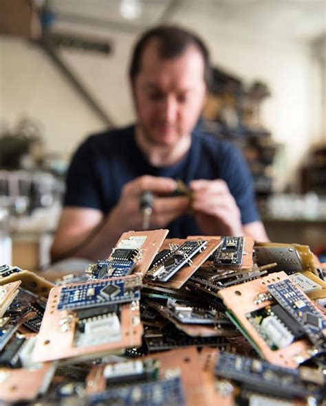 a man looking at his cell phone surrounded by electronic components