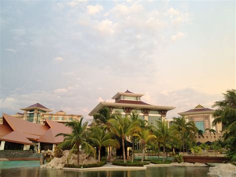 a large building sitting next to a body of water with palm trees in ...