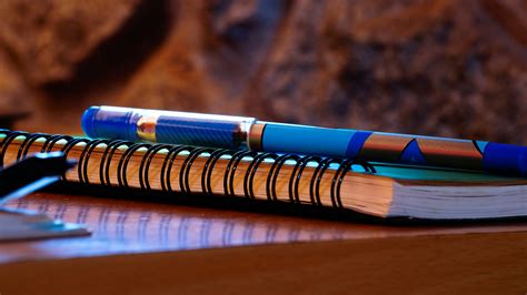 Bic Orange and White Ball Point Pens on Top of Lined Paper Notebook · Free Stock Photo