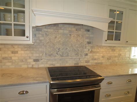 Marble subway tile installed on a kitchen backsplash with feature above the stove with a marble ...