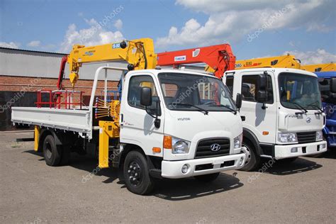 White flatbed trucks with crane arm is in the parking lot - Russia ...