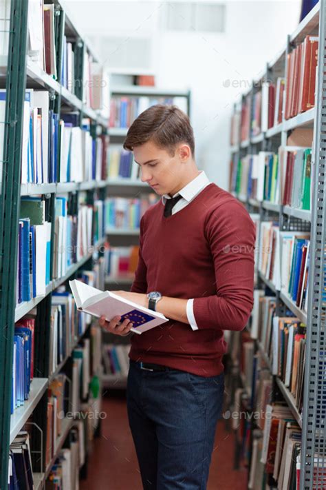 Man reading book in university library Stock Photo by vadymvdrobot