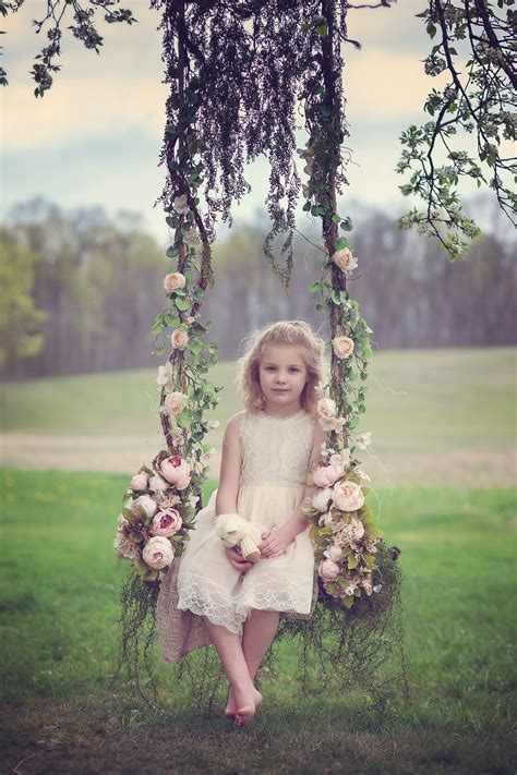 Wooden swing, flowers, and a beautiful little girl. Children ...