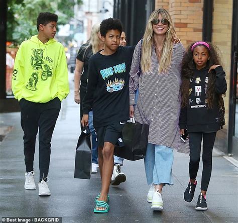 Heidi Klum cuts a quirky figure in oversize shirt and platforms as she travels with her brood in ...